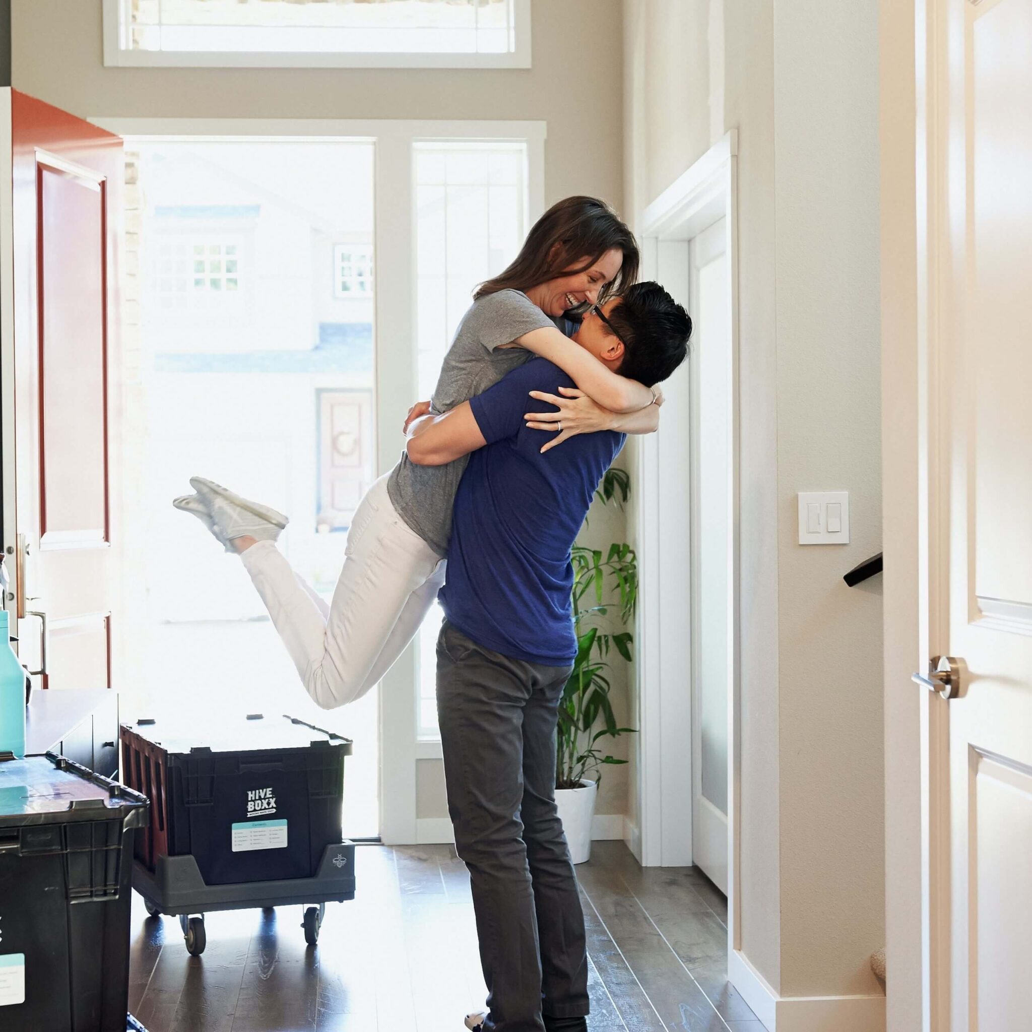 man and woman hugging showing excitement in house doorway.